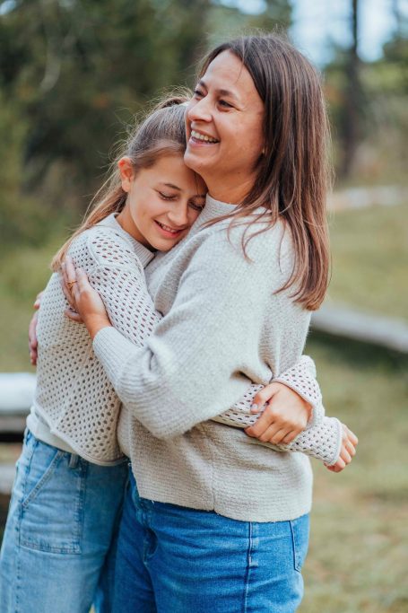 Zwei Frauen umarmen sich glücklich in einer natürlichen Umgebung.
