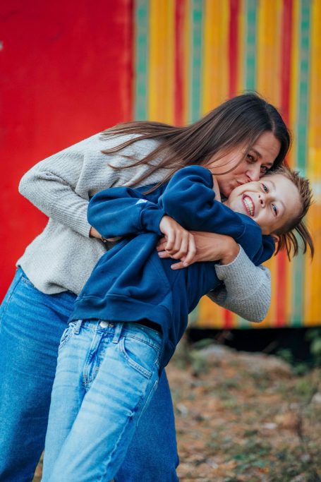 Zwei Personen umarmen sich spielerisch vor einem bunten Hintergrund.