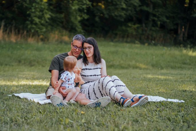 Familie sitzt auf einer Decke im Freien und genießt die Zeit miteinander.