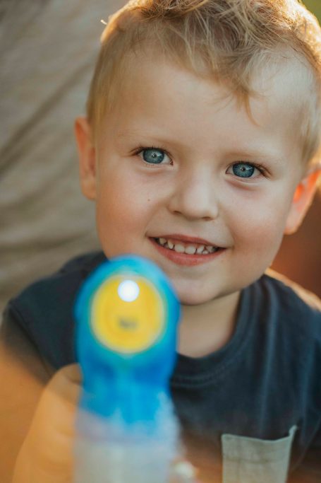 Ein strahlender Junge lächelt und hält eine Wasserpistole in der Hand.