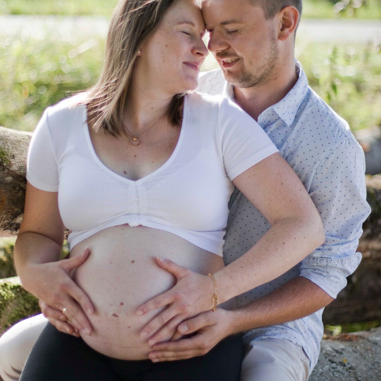 Babybauch Fotos in Main Spessart Schwangere Frau und Mann lächeln sich an, Hände auf dem Bauch platziert.