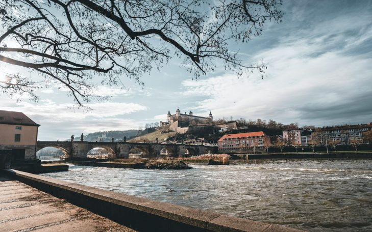 Blick auf eine Stadt mit einer Burg, umgeben von Wasser und einer Brücke.