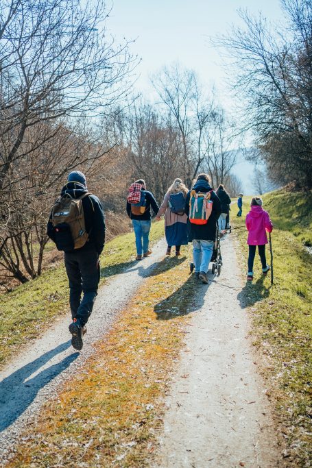Gruppe von Menschen wandert auf einem Weg durch die Natur, einige tragen Rucksäcke.
