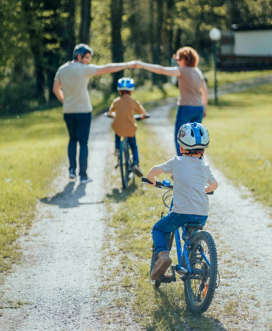 fotografin-wuerzburg Familie mit zwei Kindern auf Fahrrädern, die gemeinsam einen Weg entlang fahren.
