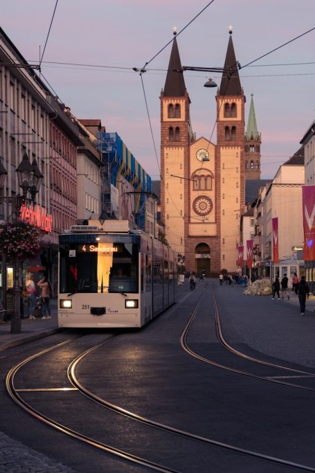 Straßenbahn biegt um die Ecke, im Hintergrund eine Kirche mit zwei Türmen.