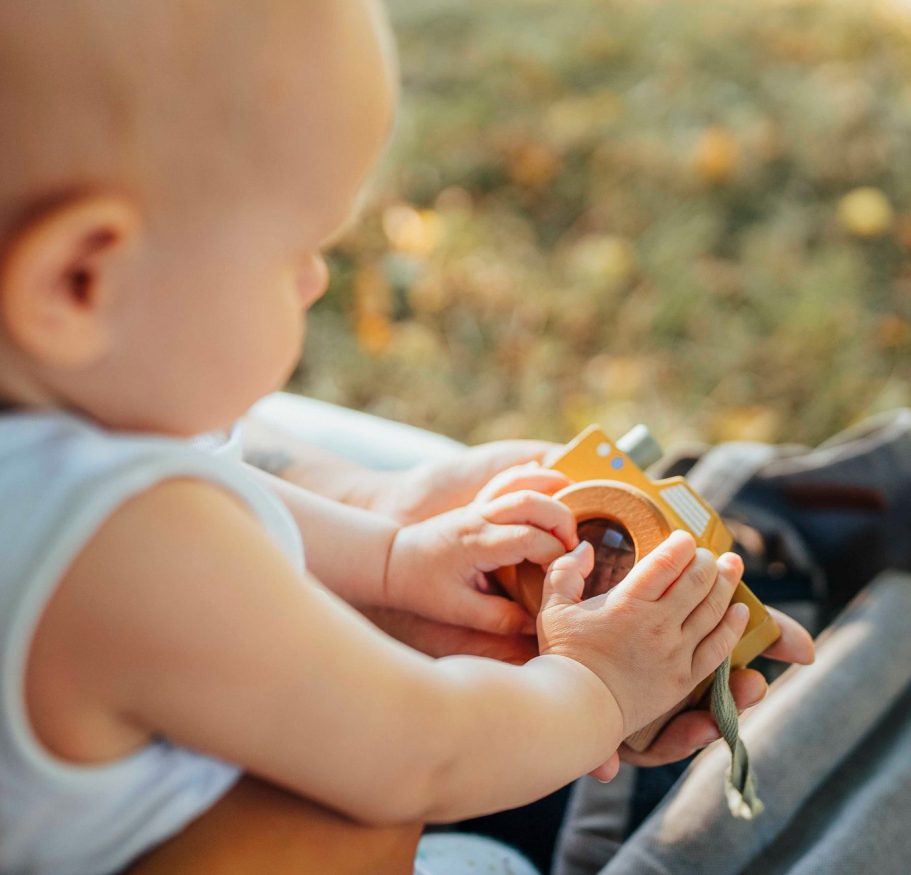 fotografin-wuerzburg Ein Kleinkind hält eine Spielzeugkamera in den Händen, umgeben von Natur.