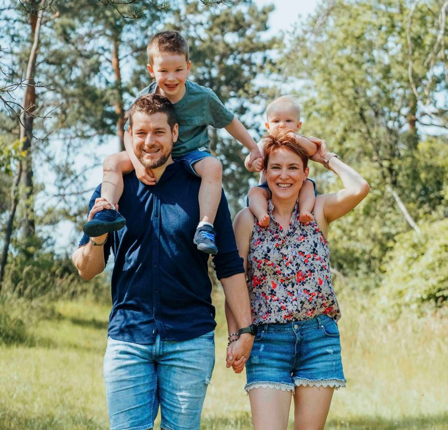 fotografin-wuerzburg Familie mit zwei Kindern, lächelnd und glücklich, spaziert in der Natur von Würzburg bei einem Familienshooting.