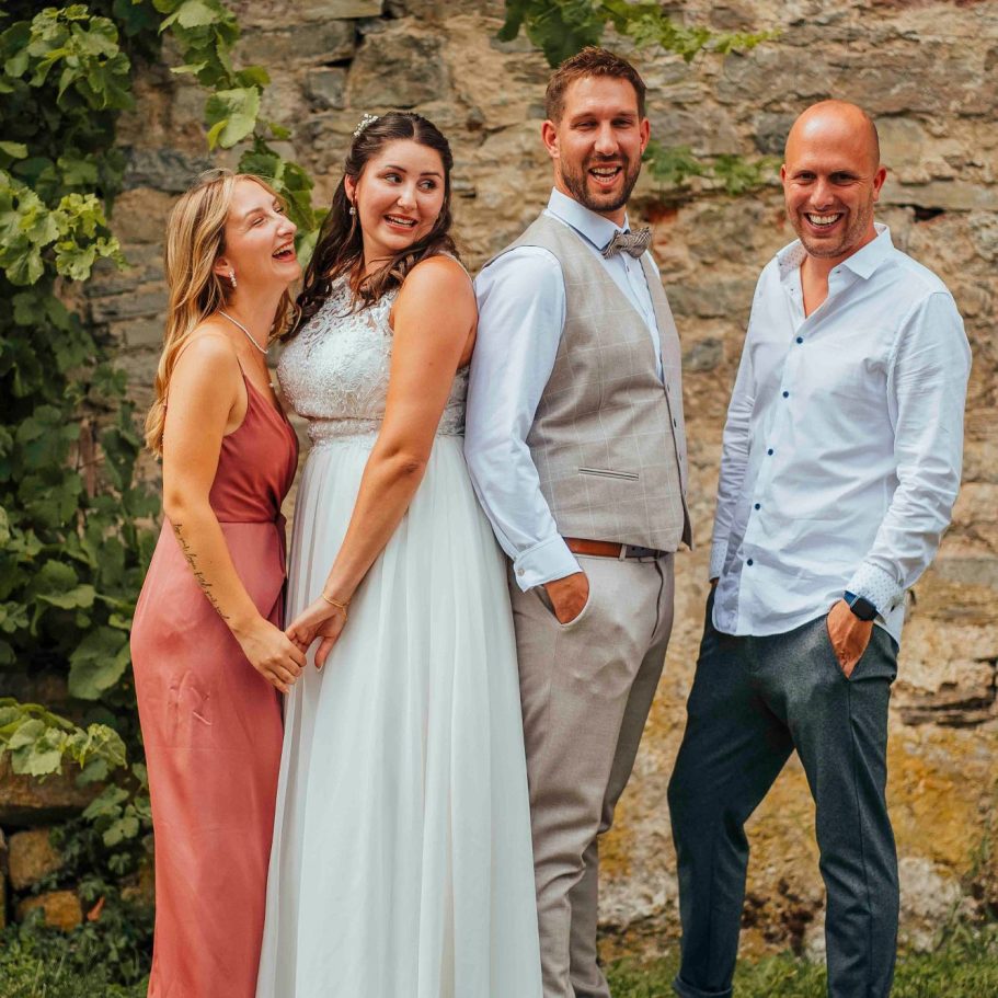hochzeitsfotos wertheim Hochzeitsfeier mit vier Personen, lächelnd vor einer Steinmauer in Wertheim