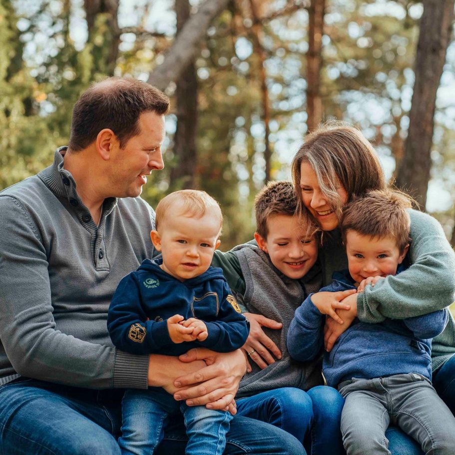 Familie mit zwei Erwachsenen und drei Kindern, gemütlich im Freien zusammen.